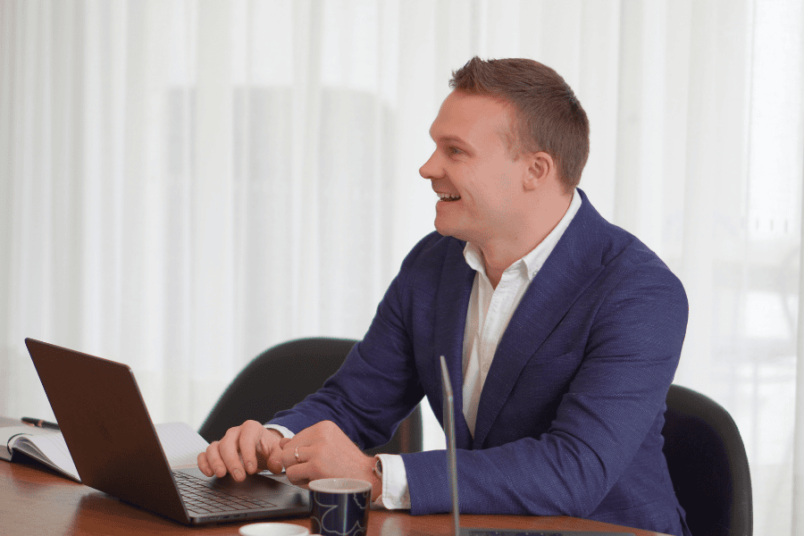 Square Labs Zoho Consultant Hugh Marshall, wearing a suit and sitting at a desk with a computer, providing Zoho consulting services